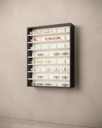 Large wall-mounted eyewear cabinet display with various sunglasses on LED shelves.