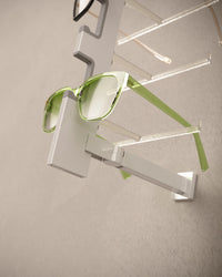 Green sunglasses on a modern wall-mounted Sunglass display rack against a neutral background