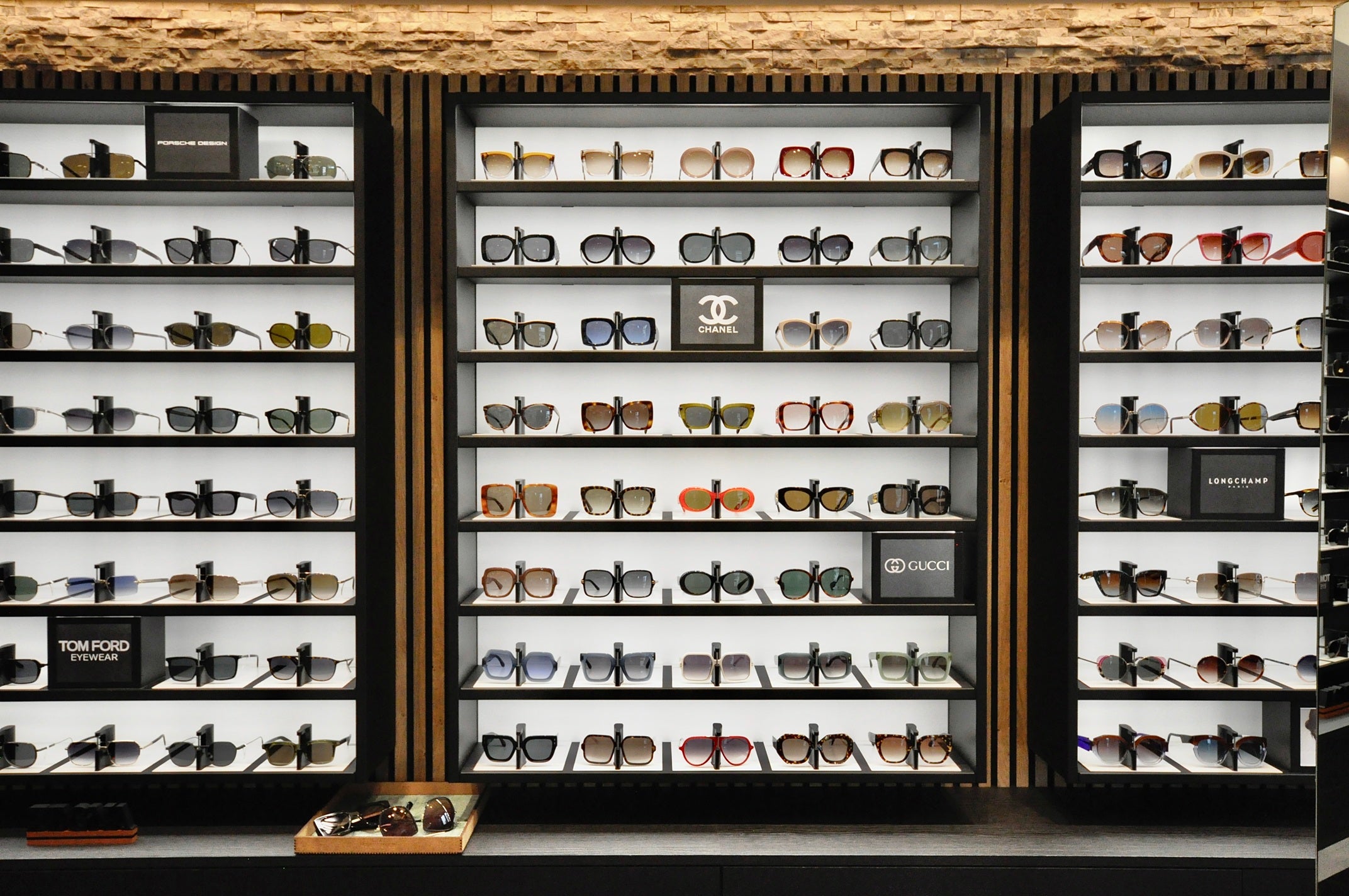 Eyewear cabinet with various pairs of sunglasses in a store setting.