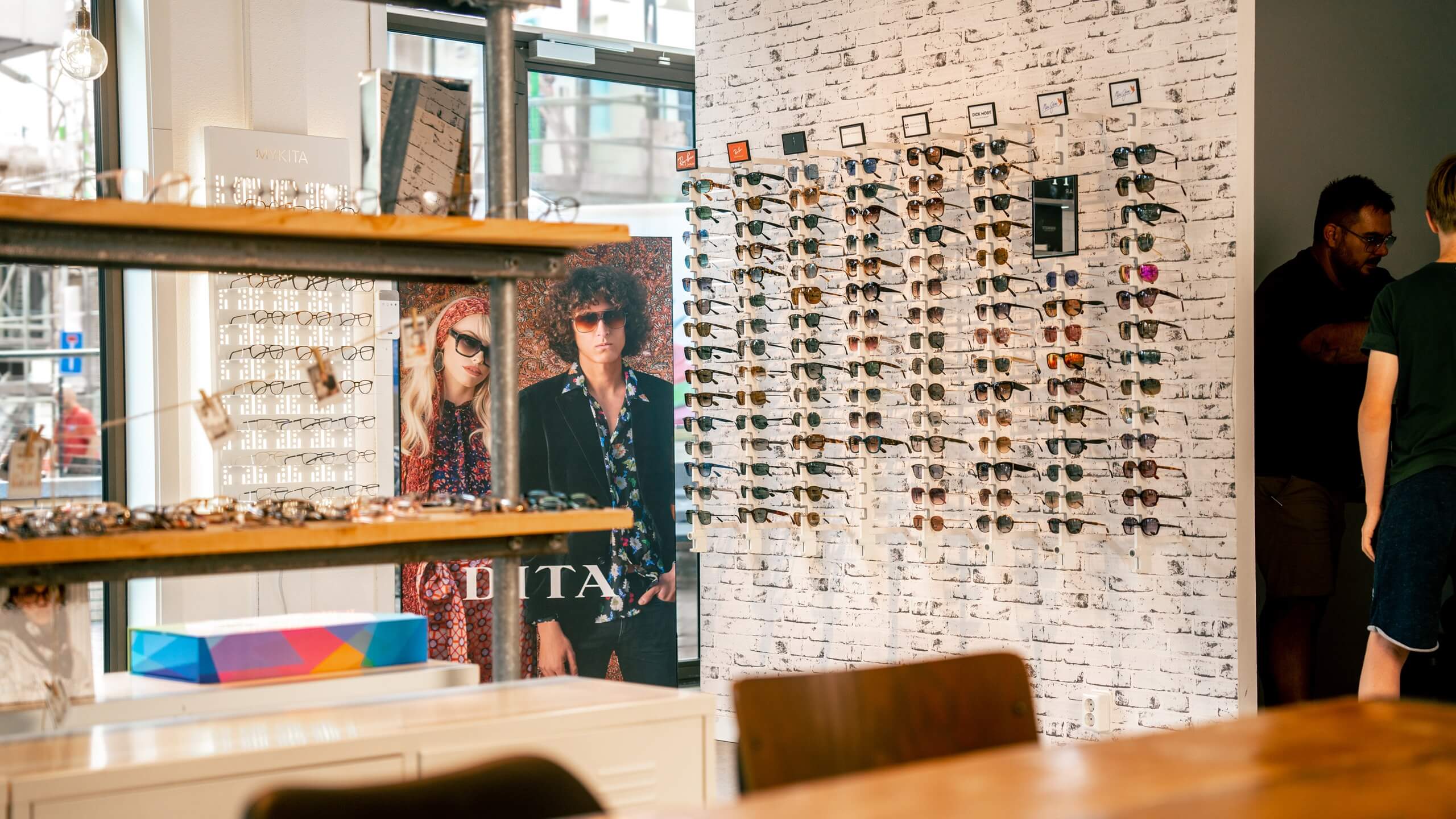 Optometry office with eyeglasses on eyewear presentation display against a white brick wall.