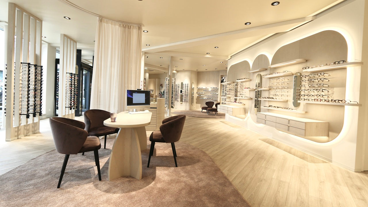 Modern optical interior of a high-end eyewear store with chairs and a table.