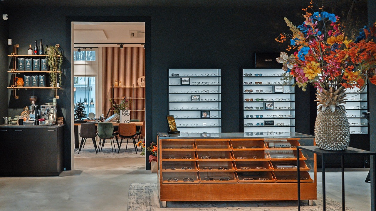 Modern optical shop design with a reception desk, cabinets, and decorative elements.