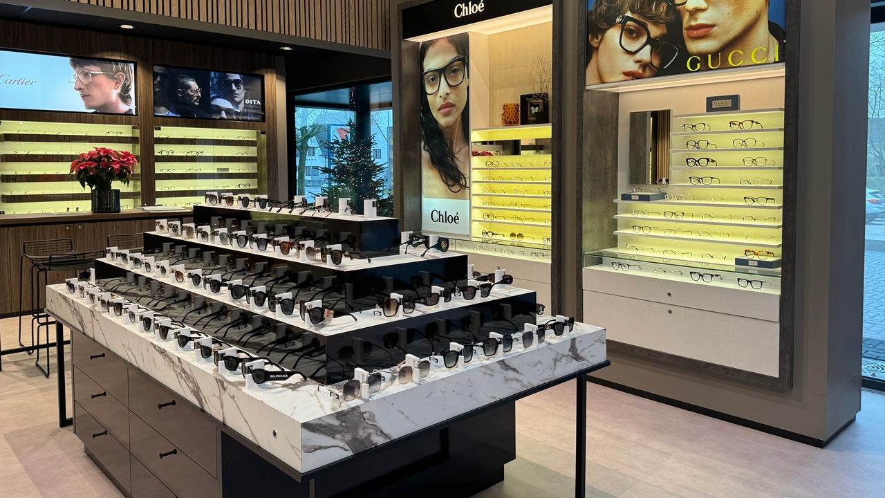 Optical store interior with locked table display for eyeglasses in subtle optical shop design.